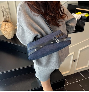 Detailed top view of blue denim baguette bag with black leather straps on a model