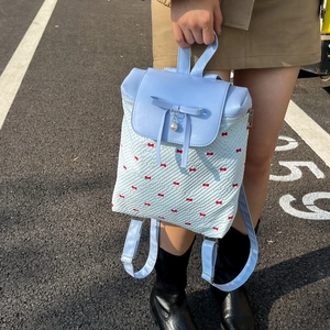 Light blue lace backpack with bow and pearl details for women on asphalt road