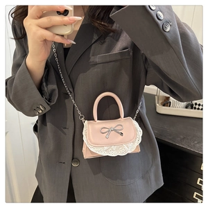 Dettaglio mini borsa rosa con fiocco d'argento e pizzo indossata da una modella