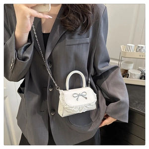 Dettaglio della mini borsa bianca con ricamo in pizzo e fiocco in metallo