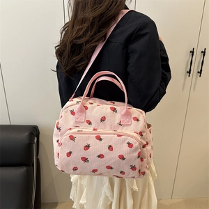 Pink corduroy crossbody bag with cute strawberry patterns shown on a female model