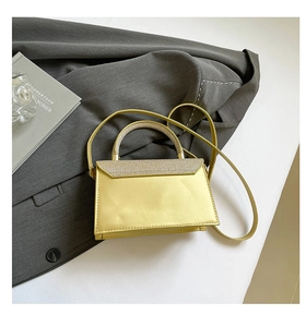 Top view of pale gold sparkling handbag with sequin details on grey blazer fabric