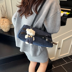 Denim patchwork baguette bag with metal buckle and teddy bear charm on model