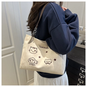 Detail of canvas tote bag featuring cute cartoon cat prints and brown leather straps