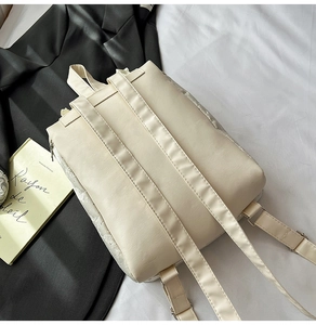 Vue détaillée du sac à dos en similicuir crème avec bordure en dentelle et bretelles
