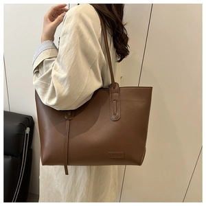 Detail view of large brown PU leather tote bag with Fashion tag and slim shoulder straps