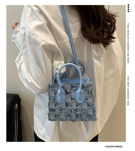 Détail du sac en jean bleu clair à damier avec des franges et des anses en cuir