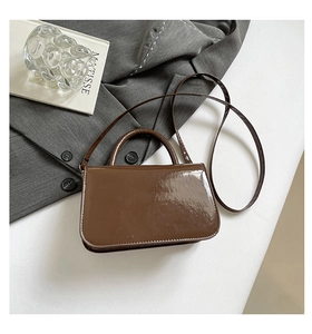 Detail of dark brown patent leather handbag with glossy finish and flap design