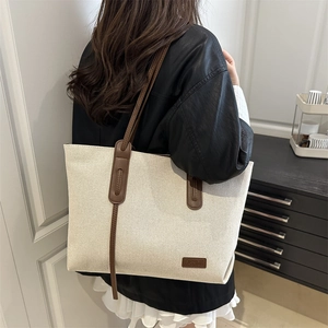 Retro canvas tote bag with brown leather handles worn by a model in a modern interior