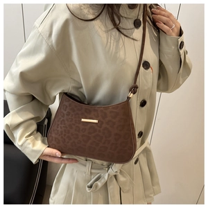 Detailed close-up of brown leopard print faux suede shoulder bag with gold metal buckle