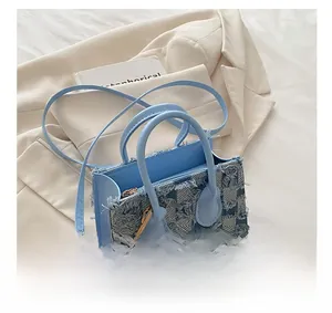 Détail d'un sac à bandoulière en denim à carreaux bleus avec bords effilochés sur blazer