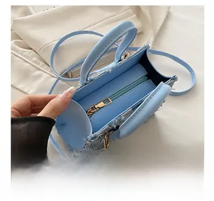 Détail d'un sac à main en denim bleu clair avec fermeture éclair fluide et bords effilochés