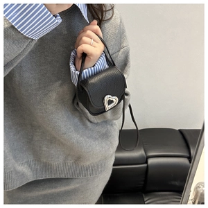Macro shot of the mini saddle bag featuring textured litchi leather and silver heart lock