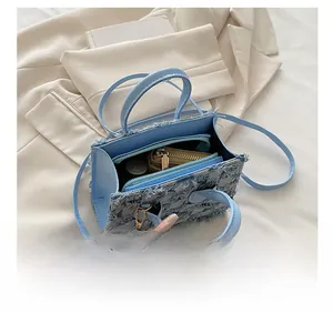 Capacité interne du sac à main en jean montrant maquillage, portefeuille et franges