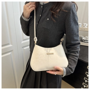 Detail of cream white underarm bag featuring leopard texture and gold buckle on model