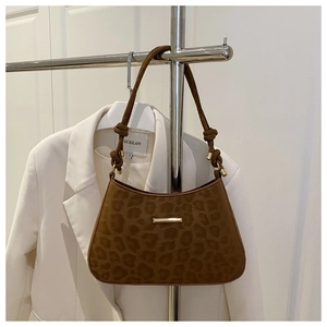 Detailed view of brown leopard print underarm bag featuring a knotted strap with gold hardware