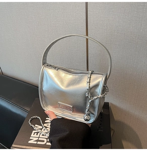 Dettaglio borsa a mano argento con logo in metallo e catena metallica intrecciata decorativa