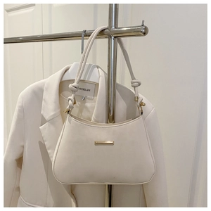 Detail of cream white leather underarm bag featuring a gold buckle and knotted shoulder strap