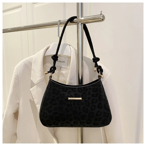 Close-up of black leopard embossed shoulder bag with gold metal bar and knot detail