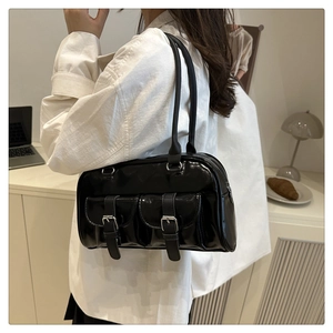 Detail of black glossy leather shoulder bag featuring silver buckles and dual pockets