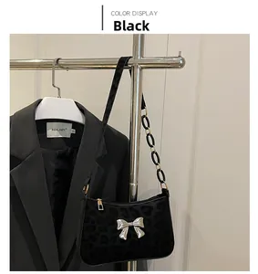 Detail of black leopard print handbag with silver butterfly buckle and ring strap