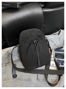 Détail du sac bandoulière noir en nylon avec étiquette orange et broderie logo