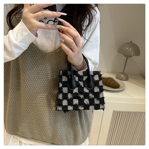 Détail du sac à main en tweed à damier avec bords effilochés et poignée rigide