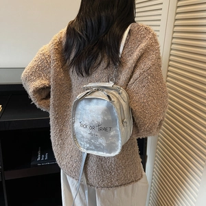 Silberner Metall-Rucksack mit Briefdruck auf Model im modischen Herbst-Look