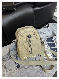 Détail du sac bandoulière en nylon olive avec fermeture à cordon et broderie de marque