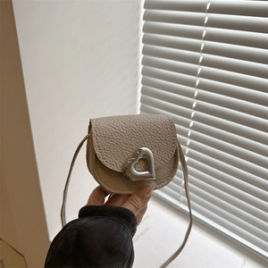 Mini sac besace beige avec boucle cœur argentée, porté main pour la taille