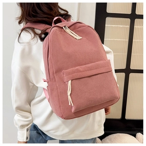 Pink corduroy backpack worn by a model showing texture and woven zipper pullers