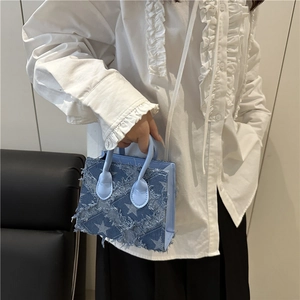 Sac fourre-tout en jean bleu avec imprimé étoiles et bords effilochés porté en bandoulière