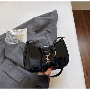 Close-up of glossy black patent leather crescent underarm bag with silver hook buckle