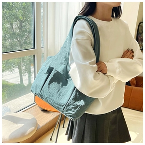 Close-up of large capacity cyan shoulder bag showing crinkled nylon texture and side pocket