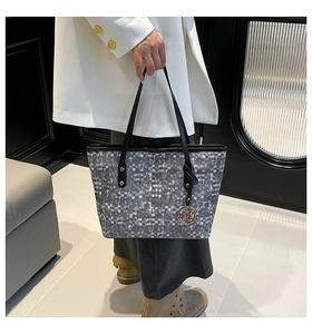 Détail du sac cabas gris à carreaux avec logo doré et pendentif métallique élégant