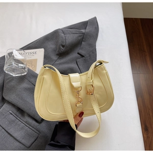 Detailed view of the yellow crescent underarm bag featuring a vintage gold metal hook clasp