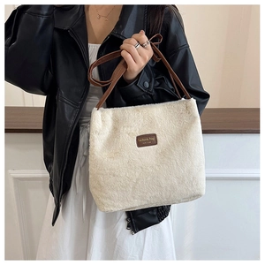 Gros plan du sac fourre-tout en peluche blanche avec anses en cuir marron et étiquette
