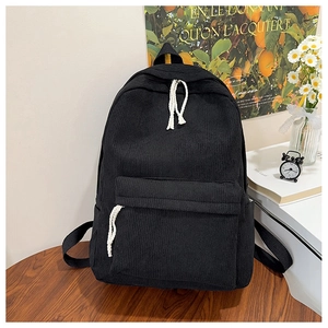 Detail of black corduroy backpack showing high-density texture and white rope zipper pull