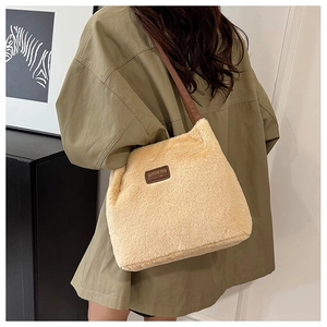 Détail du cabas en peluche beige avec bandoulière en cuir brun et écusson