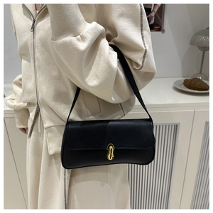 Détail d'un sac sous le bras en cuir grainé noir avec un fermoir rotatif doré chic