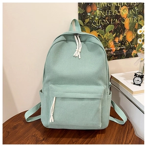 Close-up of mint green corduroy backpack showing vertical texture and white cotton rope pulls