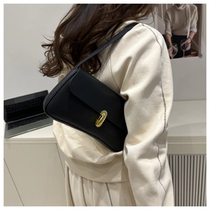 Détail d'un sac porté épaule noir à texture litchi avec fermoir doré tournant