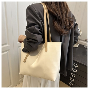 Detailed view of off-white tote bag with sleek vertical stitching and brown shoulder straps