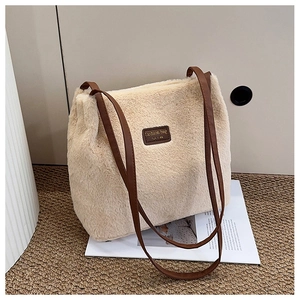 Détail d'un sac cabas en peluche beige avec écusson en cuir marron et fines lanières