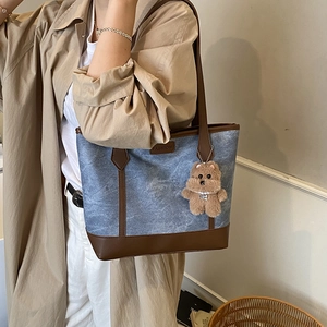 Large denim and leather patchwork tote bag with a plush bear charm for daily commute