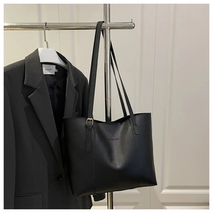 Close-up of black leather tote bag with engraved fashion logo and gold metal buckle