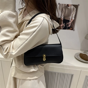 Sac sous le bras classique en cuir noir avec fermoir doré porté par le mannequin