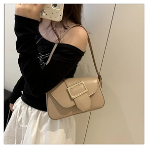 Selfie miroir montrant un sac sous le bras en cuir beige avec une grande boucle dorée