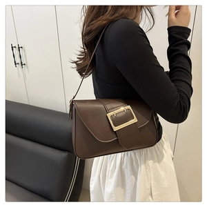 Détail du sac à bandoulière en cuir marron foncé vintage avec une grande boucle dorée