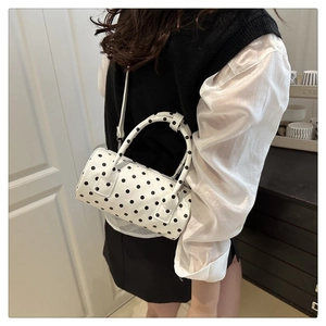 Detailed shot of cylinder polka dot handbag with dual handles and crossbody strap